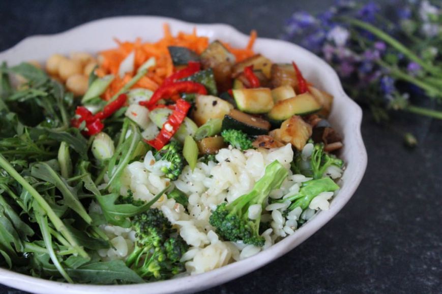 Buddha Bowl with boiled rice, rocket, broccoli, courgette, grated carrot and chickpeas, topped with spring onions and chilli slices.
