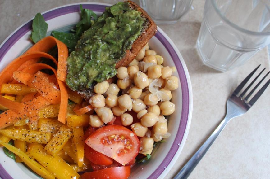 Buddha Bowl with Carrot Ribbons, Pepper Slices, Tomato Quarters, Chickpeas, Rocket and Smashed Avocado on Homemade Brown Bread.